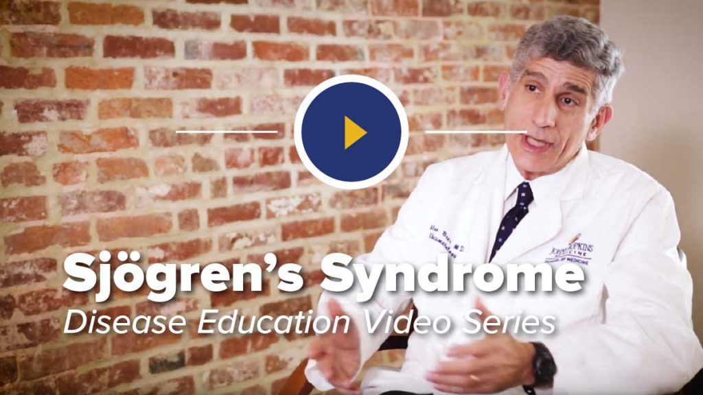 Dr. Alan Baer in Chair in Front of Brick Wall Discussing Sjögren’s Syndrome